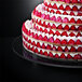 A close-up of a large cake on a Matfer Bourgeat Plexiglass cake stand with strawberries on top.
