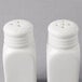 Two white ceramic American Metalcraft salt and pepper shakers.