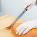 A person cutting bread with a Victorinox serrated bread knife.