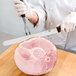 A person in white gloves using a Victorinox Granton Edge Slicing / Carving Knife to cut ham.