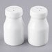 Two white ceramic bottle salt and pepper shakers on a gray surface.