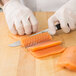 A person in a white glove using a Mercer Culinary Z&#252;M Stiff Boning Knife to cut a piece of salmon on a wooden cutting board.