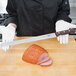 A person in white gloves using a Victorinox slicing and carving knife to slice ham.
