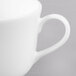 A close-up of a white bone china tea cup with a handle.