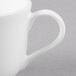 A close-up of a white Reserve by Libbey bone china coffee cup with a handle.