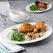 A Reserve by Libbey bone china oval platter with a plate of fried chicken and green beans on a table.