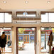 A Schwank surface mounted air curtain over a store entrance with a couple of people in front of it.