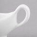 A close-up of a white Reserve by Libbey sauce boat with a handle.