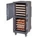 A Cambro tall profile charcoal gray food holding cart with trays of food.