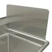 A close-up of a stainless steel sink with a removable metal side splash.