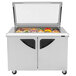 A Turbo Air stainless steel refrigerated sandwich prep table with glass lids over food trays.