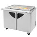 A Turbo Air stainless steel sandwich prep table with glass lids over the refrigerated area.