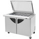 A stainless steel Turbo Air refrigerated sandwich prep table with glass lids over the top.