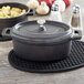 An American Metalcraft black cast iron oval dutch oven with a lid on a table.