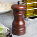 A Fletchers' Mill walnut stain wooden pepper mill on a table.