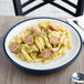 A dark blue Dinex Insul-Base meal delivery plate with a plate of pasta with sausage and pesto sauce.