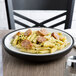 A close up of a Dinex Onyx insulated meal delivery base with a plate of pasta with sausages and pesto sauce.