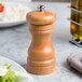 A Fletchers' Mill cherry wooden pepper mill next to a plate of salad.