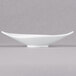 A white Arcoroc porcelain bowl with a curved edge on a gray surface.