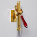 A brass-plated Franmara Bar-Pull wine bottle opener with a red handle.