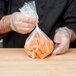 A person in a chef's uniform holding a LK Packaging plastic food bag of carrots.