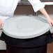A person holding a gray lid over a Continental 32 gallon trash can.