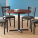 A Lancaster Table & Seating standard height table base column and rod on a table with chairs around it.