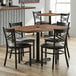 A Lancaster Table & Seating cast iron spider table base on a table with black metal legs and chairs.