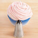 A cupcake with pink frosting on top with a silver Ateco 846 closed star piping tip nozzle.