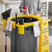 A man standing next to a yellow Rubbermaid Brute caddy attached to a yellow trash bin.