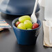 A bowl of grapes with a Cambro navy blue insulated plastic bowl filled with green grapes and a fork.
