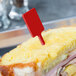 A sandwich with a red rectangular pick sticking out of it.