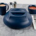 A blue plastic container with a navy blue Cambro plate cover on it and a bowl of tomato soup.