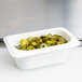 A white Cambro plastic food pan with green jalapenos in it.