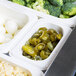 A white Cambro food pan with broccoli, eggs, and green peppers on a counter.