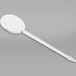 A white plastic spoon with a long tip.