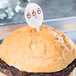 A close up of a burger with a white oval pick on top.