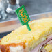 A sandwich with a WNA Comet green rectangular pick on a farm-to-table restaurant counter.