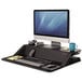 A Fellowes Lotus sit-stand workstation with a computer, keyboard, and phone on it.