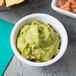 A white Tablecraft ramekin filled with guacamole on a table with salsa.