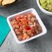 A white square Tablecraft ramekin filled with salsa on a table with a bowl of guacamole.