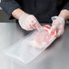 A person wearing gloves vacuum sealing meat in a ARY VacMaster full mesh bag.