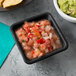 A Tablecraft black square ramekin filled with salsa and guacamole on a table in a Mexican restaurant.
