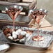 Two copper martini glasses filled with chocolate and nuts on a tray.