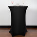 A black Snap Drape spandex table cover on a round table with two wine glasses on it.