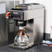A Bunn commercial automatic coffee maker with plastic funnel and glass coffee pot on a counter.