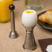 A hard boiled egg in a Tellier stainless steel egg topper stand.