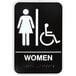 A black and white Vollrath restroom sign for women with a wheelchair icon and Braille.