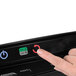 A finger pressing a button on a Fellowes Neptune 3 Laminator.