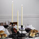 A table set with food, drinks, and ivory taper candles.